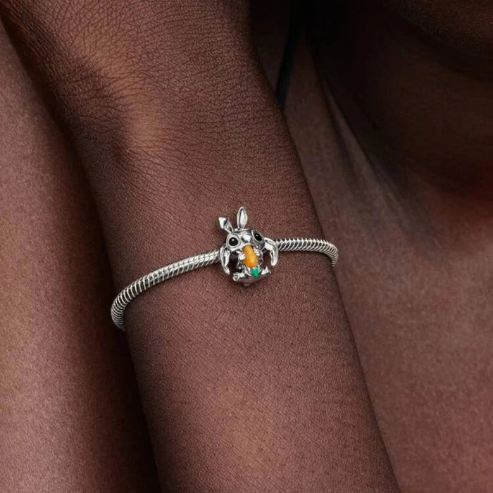 Silver bracelet with a bunny charm on a wrist against of a women