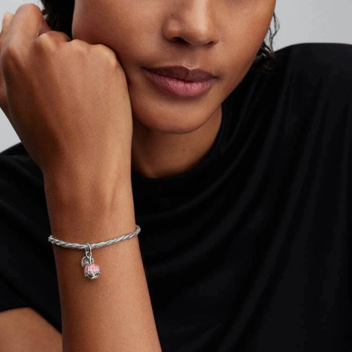 Silver bracelet with a flower-shaped charm on the wrist of a women