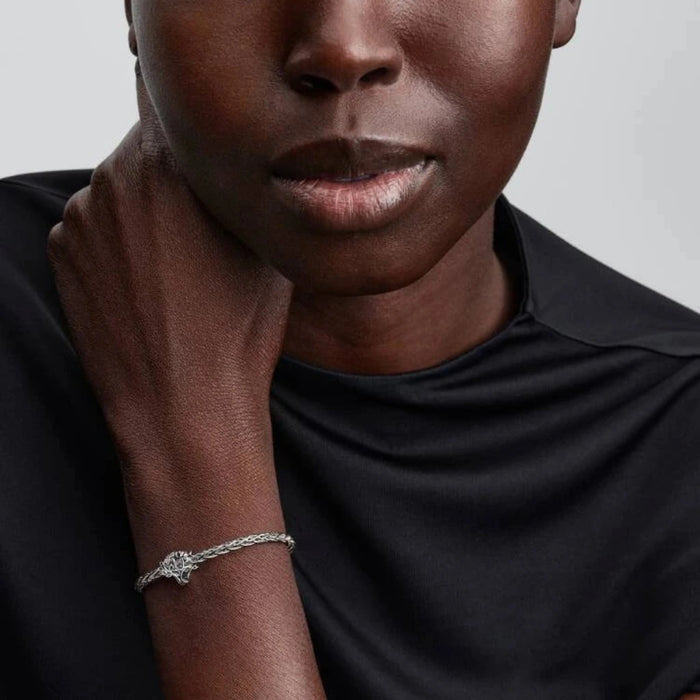 Silver bracelet with a tree-shaped charm on the wrist of a women
