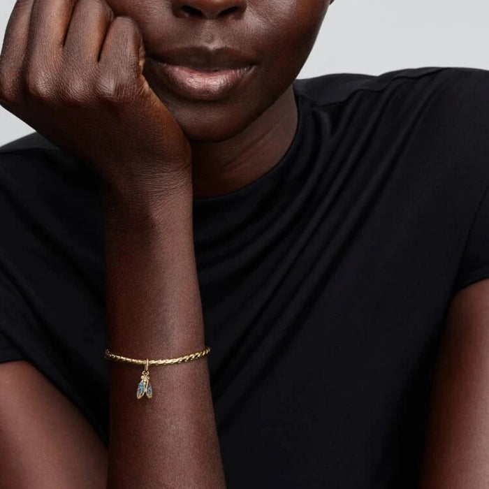 Gold bracelet with a cicada-shaped charm on the wrist of a women