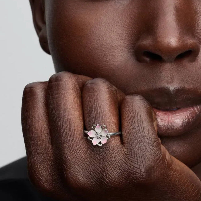 Close-up of a woman's hand wearing a floral ring with a neutral background