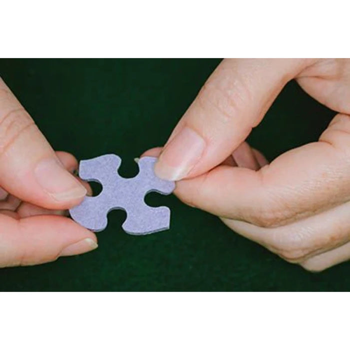 An individual holding a single puzzle piece, contemplating its placement in a larger jigsaw puzzle.  