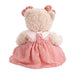 A teddy bear in a pink dress is displayed on a white surface.