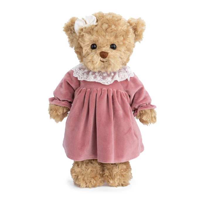 A teddy bear wearing a pink dress, sitting upright with a friendly expression.