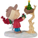 Figurine of a character from Peanuts series with a Christmas tree and presents on a branch.