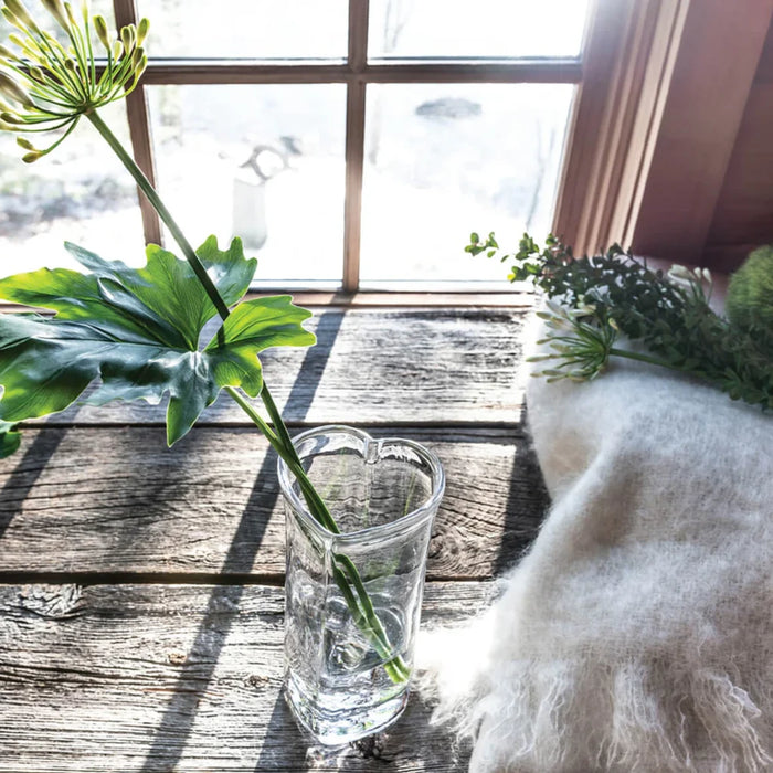 A decorative vase holding water and a flourishing plant with lush foliage.