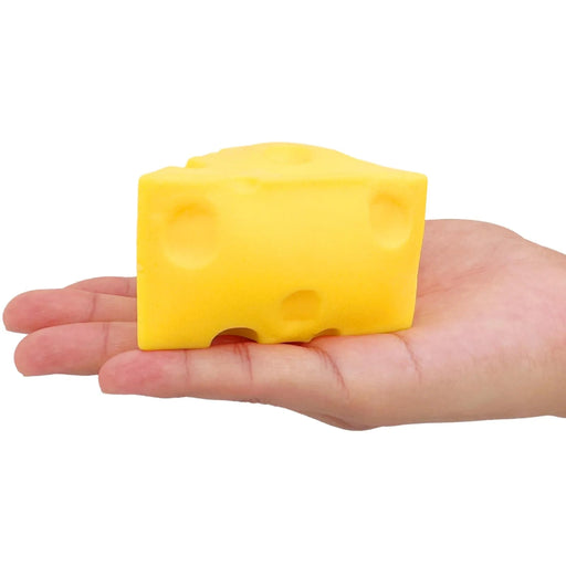 Yellow cheese-shaped block held in a hand against a white background