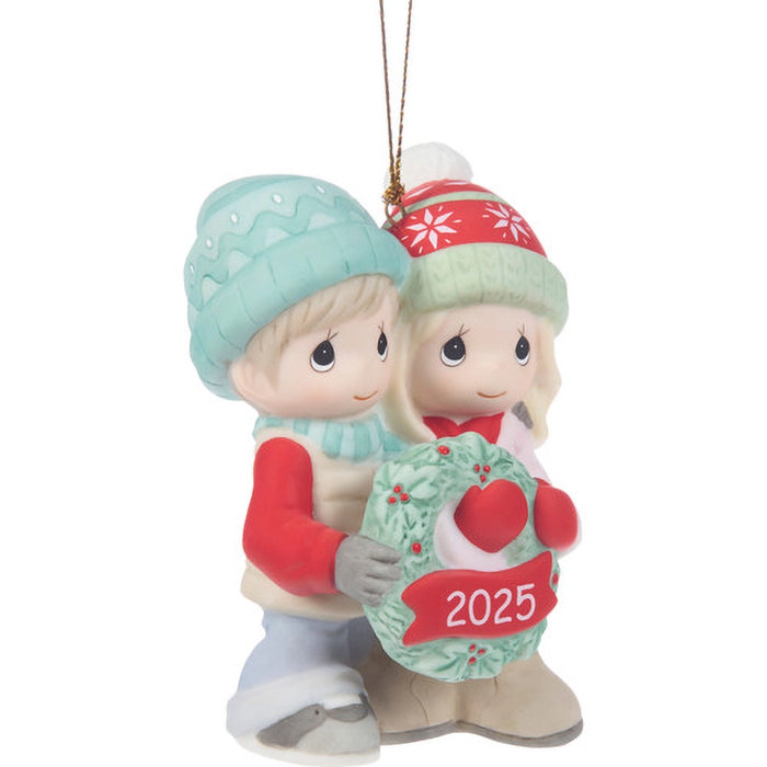 Christmas ornament of two children holding a wreath with '2025' on a white background