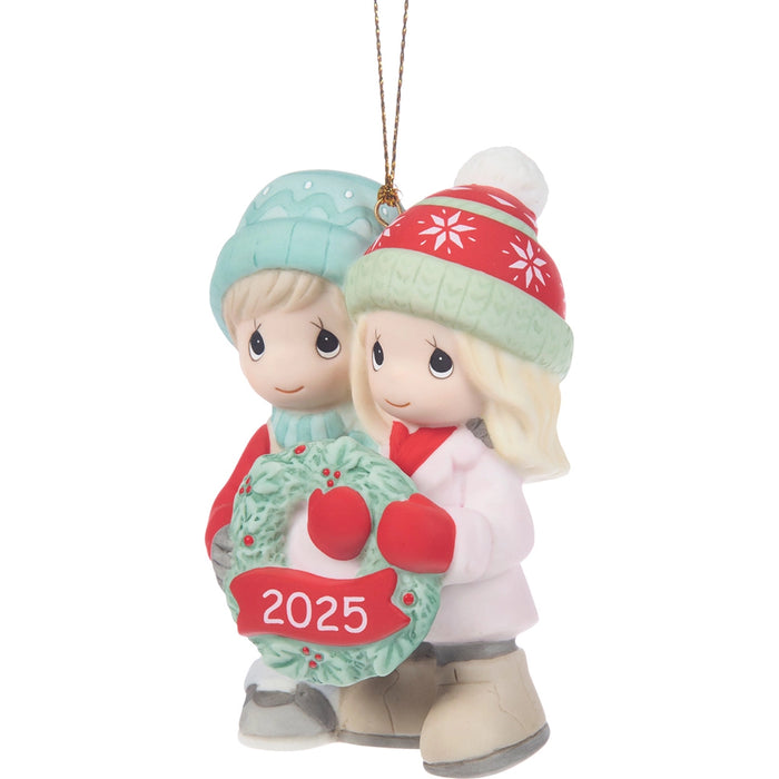 Christmas ornament with two children holding a wreath labeled '2025' on a white background