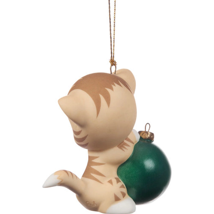 Cat-shaped ornament holding a green ball on a white background