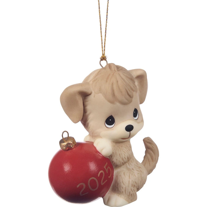 Dog ornament holding a red ball with '2025' on it, hanging from a string.