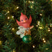 Decorative Christmas ornament with a pink bird and green ball labeled '2025' on a lit Christmas tree.