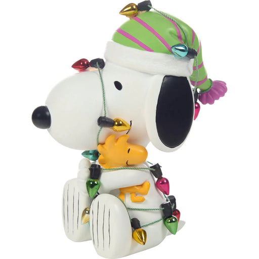 Decorative figurine of a Snoopy with a green hat and Christmas lights on a white background