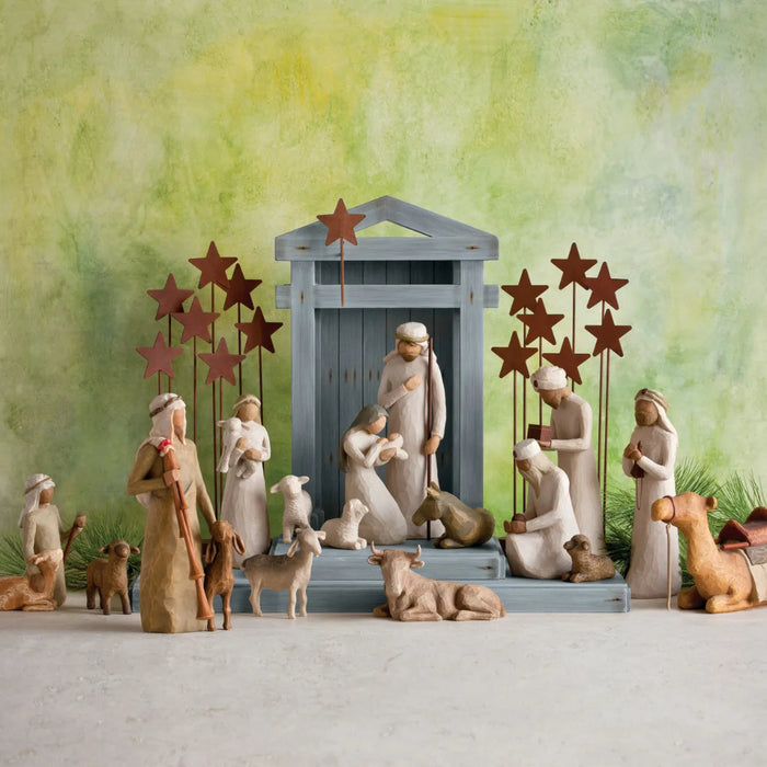 Nativity scene with figures and star decorations against a green background