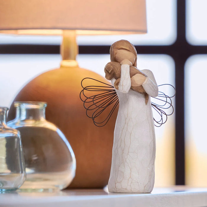 Decorative angel figurine holding a child in front of a lamp and glass jars.