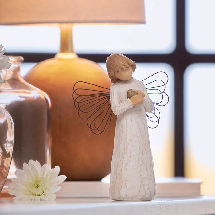 Angel figurine holding a bird on a table with a blurred background