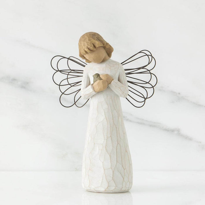 Angel figurine with outstretched wings holding a baby on a marble background