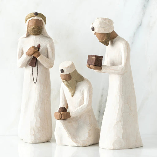Three ceramic figures in traditional attire on a white background