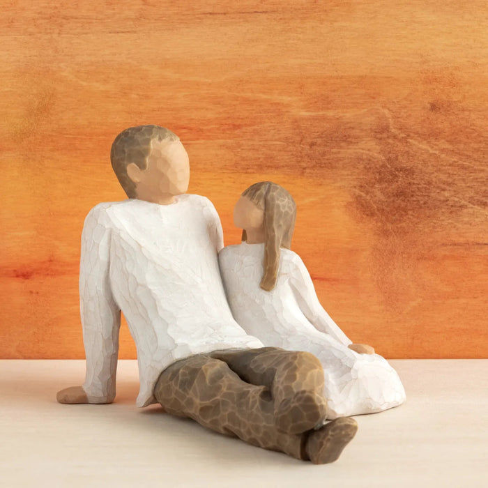 Figurine of a Father and Daughter Sitting together  with a wooden background 
