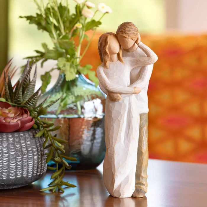 Statue of a couple embracing with plants and a colorful background