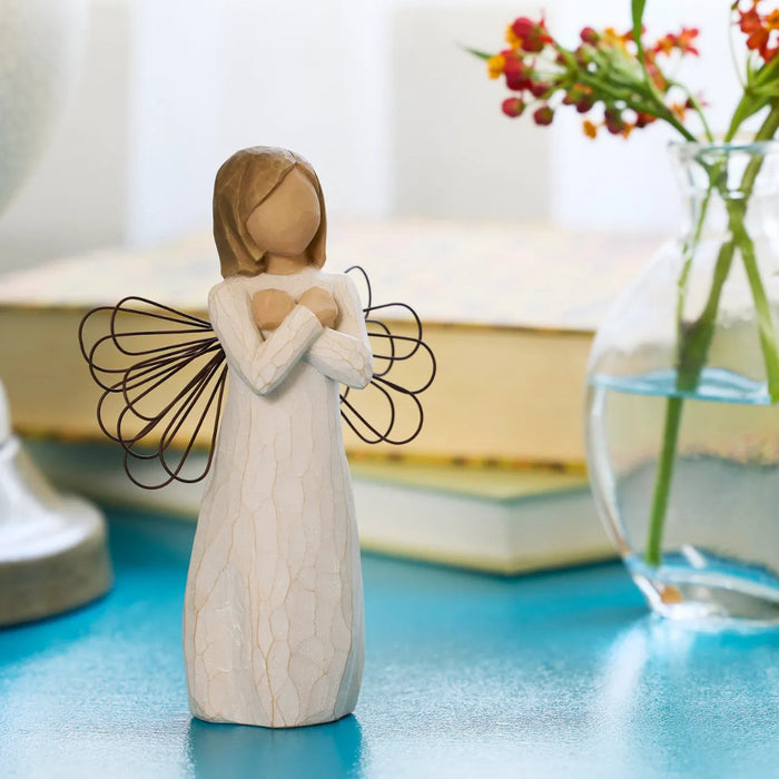 Decorative figurine of a woman with angel wings on a blue surface.