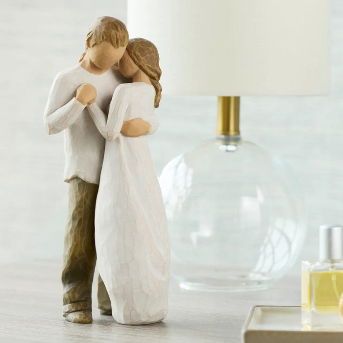 Statue of a couple embracing on a table with a lamp in the background