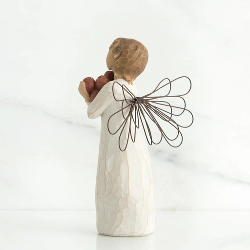 Decorative angel figurine holding two apples on a white background