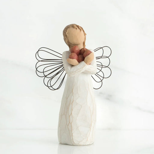 Angel figurine holding apples  on a white background
