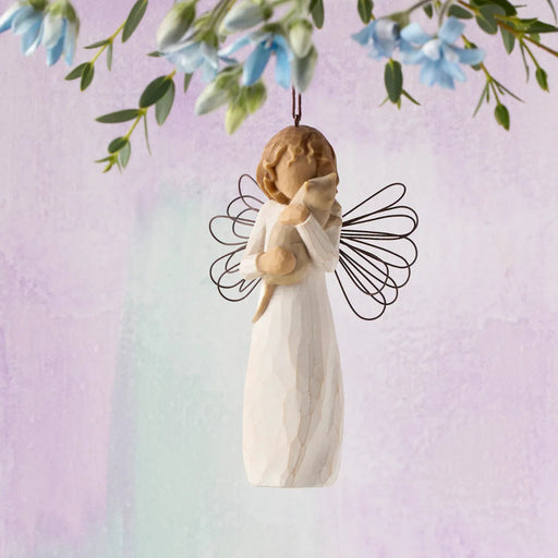 Angel figurine with outstretched wings hanging from a branch with flowers on a pastel background