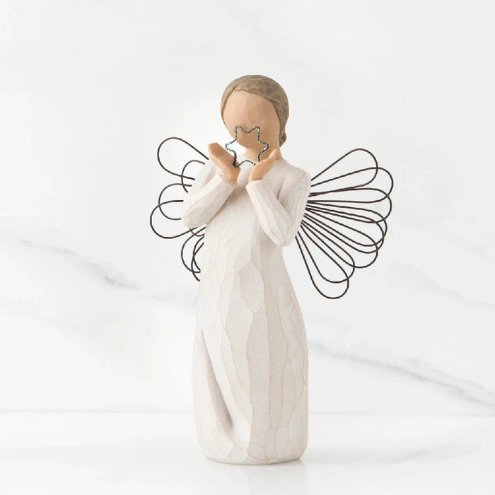 A willow tree angel holding a heart, symbolizing love and serenity in a peaceful outdoor setting.