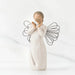 A willow tree angel holding a heart, symbolizing love and serenity in a peaceful outdoor setting.