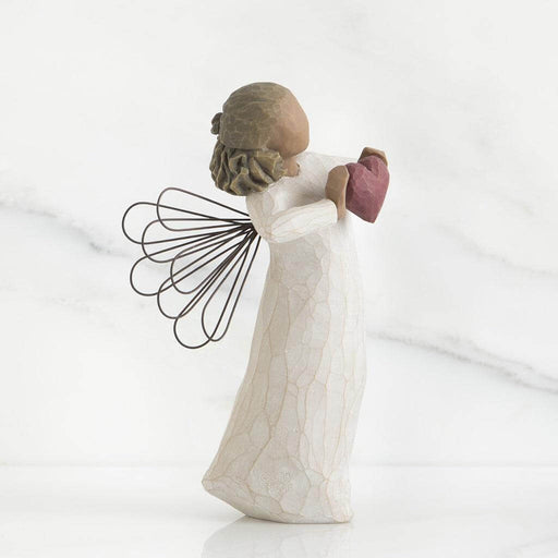 Angel figurine holding a heart and a fan on a white background