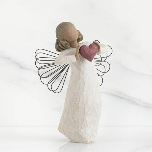 Angel figurine holding a heart on a white background