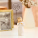 Small figurine of a person holding a balloon with 'miss you' text, next to a framed photo on a surface.