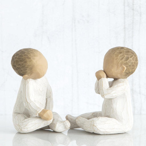 Two ceramic figures of children sitting on a white background