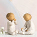 Two stone sculptures of children sitting on a surface with a light background