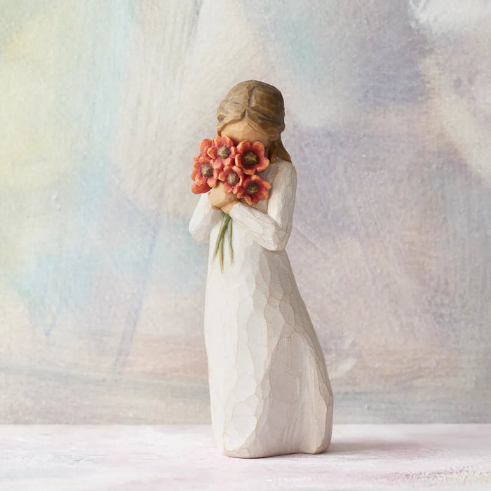 Statue of a woman holding flowers against a soft, multicolored background