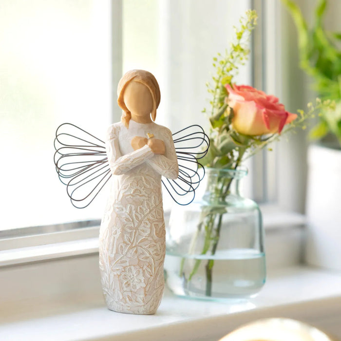 Decorative angel figurine with a vase of flowers on a windowsill