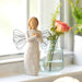 Decorative angel figurine with a vase of flowers on a windowsill