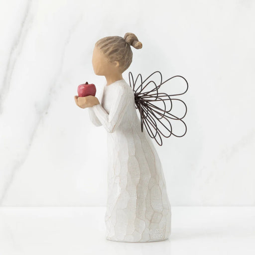 Decorative figurine of a woman holding an apple against a white background