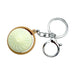 Keychain with a round, light-colored object inside a wooden-like casing on a white background