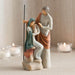 Statue of a couple with a child, set against a neutral background with candles.