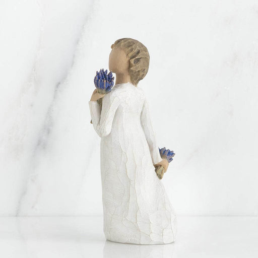 Statue of a person holding blue flowers against a white background