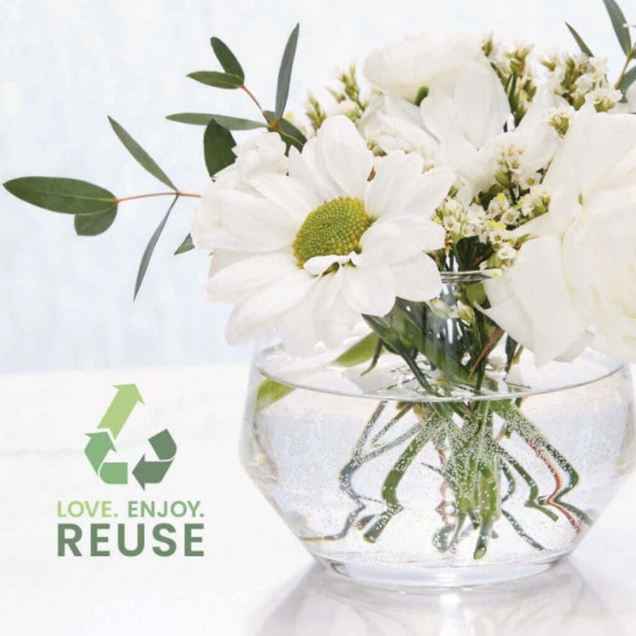 Clear glass vase with white flowers and green leaves on a light background with 'Love. Enjoy. Reuse' text.