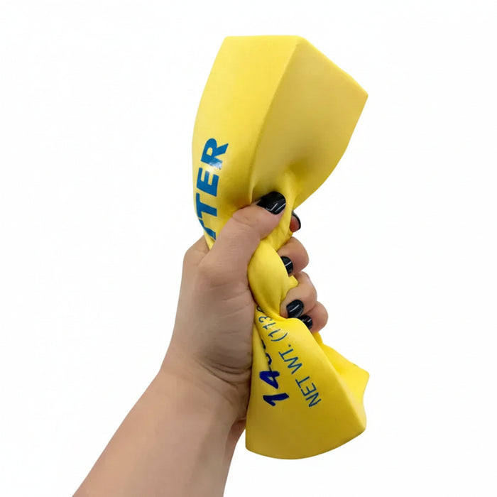 Yellow butter squishy  held by a hand with black nail polish on a white background