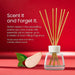 Yankee Candle reed diffuser bottle with natural reed sticks, shown on a red background with promotional text and a sliced apple with green leaves.