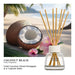 Yankee Candle Coconut Beach fruity fragrance diffuser with a glass bottle, clear liquid, white cap, and natural reed sticks, shown in front of a tropical beach scene with a coconut, pink flowers, and palm leaves. Text below reads 'COCONUT BEACH' and 'Fresh Coconut, Sliced Pineapple & a Tropical Oasis'.