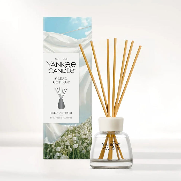 Yankee Candle Clean Cotton reed diffuser set with a clear glass bottle, white cap, natural wood reeds, and the matching product box featuring white cotton imagery.