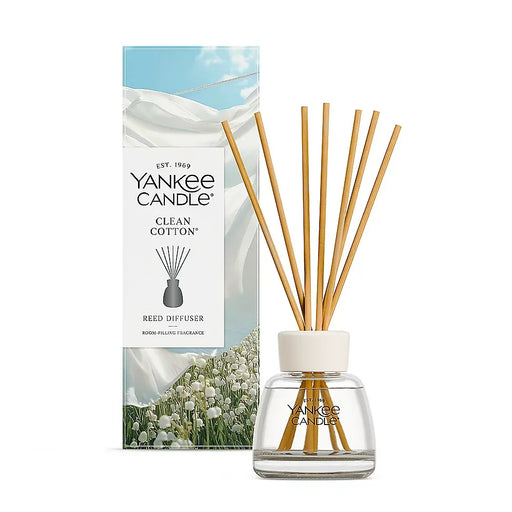 Yankee Candle Clean Cotton reed diffuser with a clear glass bottle, white cap, and natural wood reeds, shown next to its white and blue packaging box.