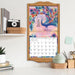 Decorative calendar with peacock design on a shelf with office supplies
